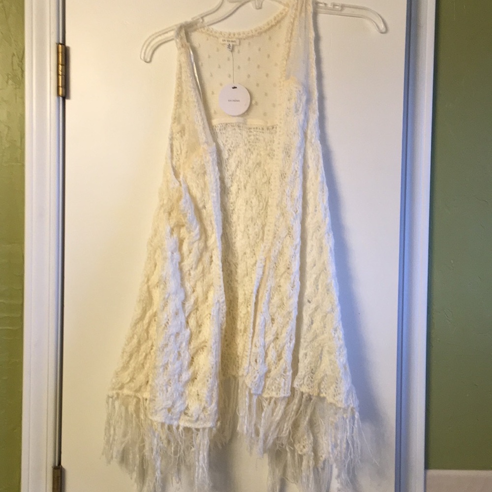 Crochet cream colored vest with fringed bottom.